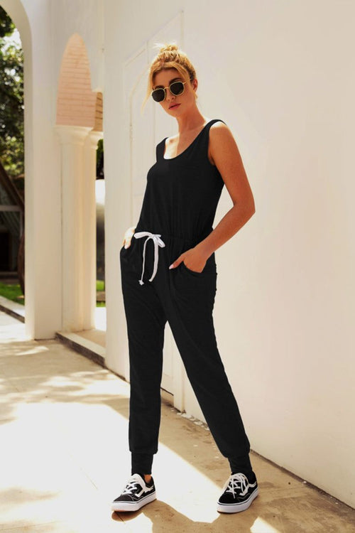 Woman wearing black comfy sleeveless vest pocket jumpsuit with elastic waistband and drawstring outdoors