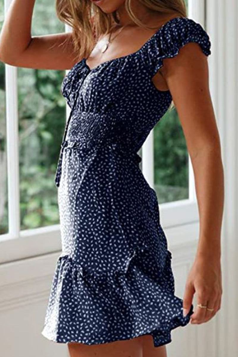 Woman wearing navy blue sweetheart collar printed ruffled maxi dress with high waist and cap sleeves.