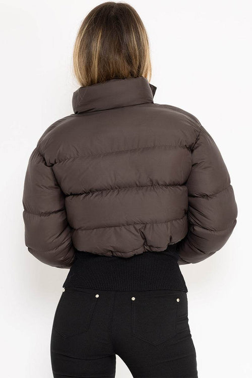 Brown cropped puffer jacket with high collar and quilted design, worn by a woman from the back.