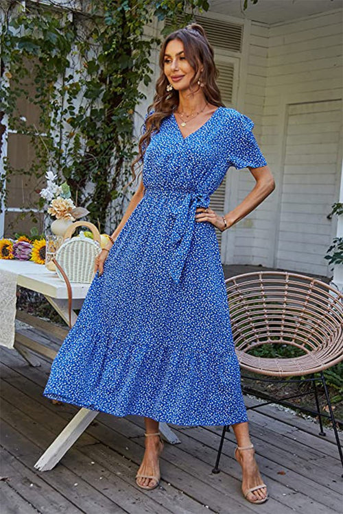 Woman wearing a blue Charming Floral Boho Maxi Dress with wrap V-neck and belted waist on a porch setting