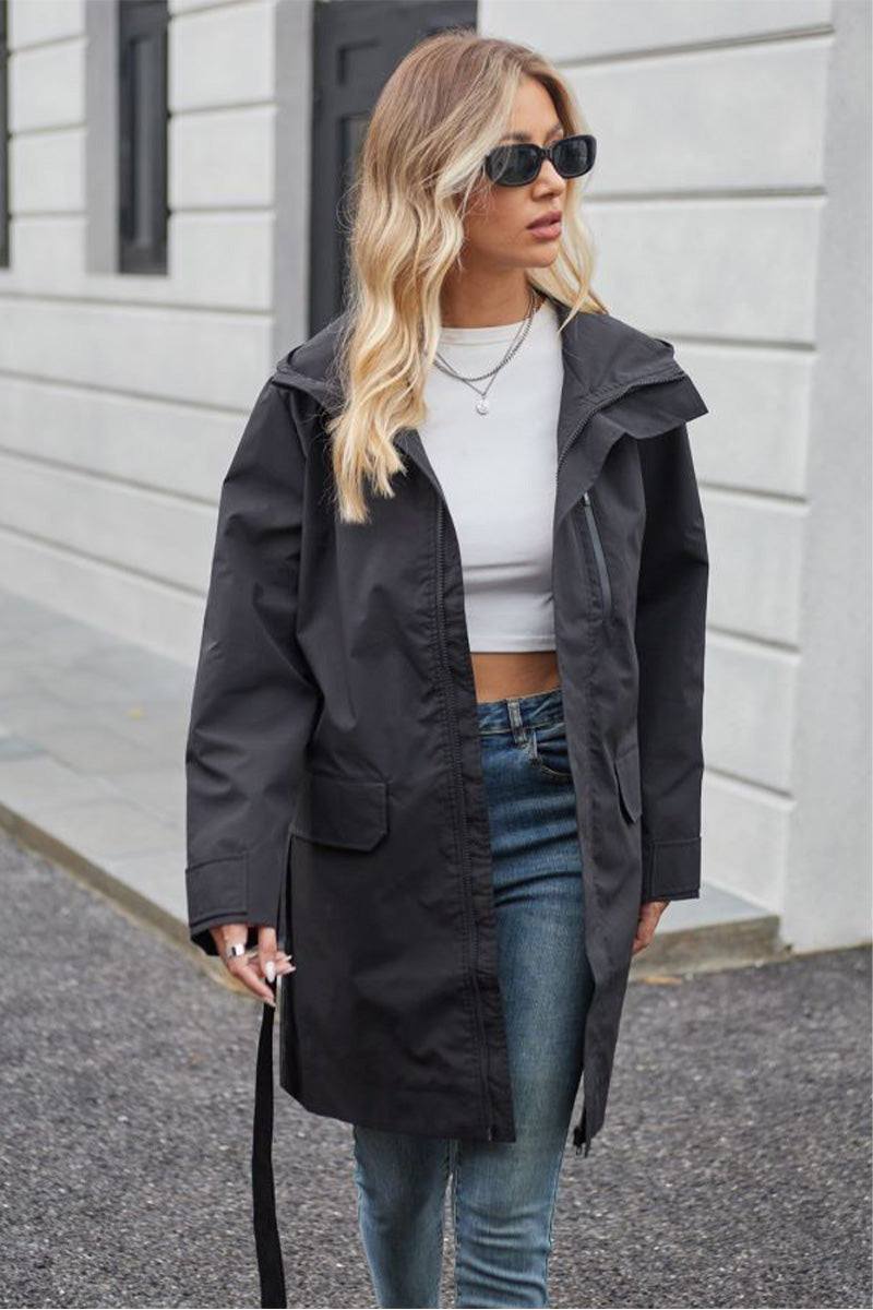 Woman wearing a black water-resistant windbreaker trench jacket with belt over casual outfit outdoors