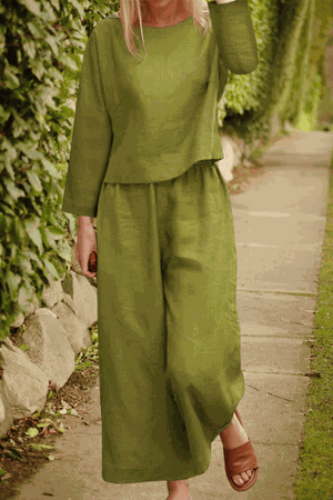 Woman wearing loose solid color two-piece set in olive green with long sleeves and wide-leg pants outdoors