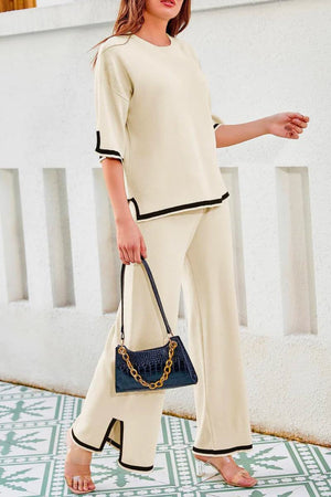 Short sleeved relaxed fit two-piece lounge set in cream with black trim, featuring a loose top and wide-leg palazzo pants.