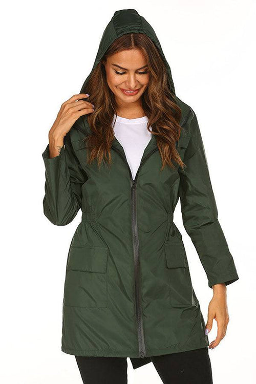 Woman wearing green outdoor and travel hooded raincoat windbreaker jacket with front zipper and pockets