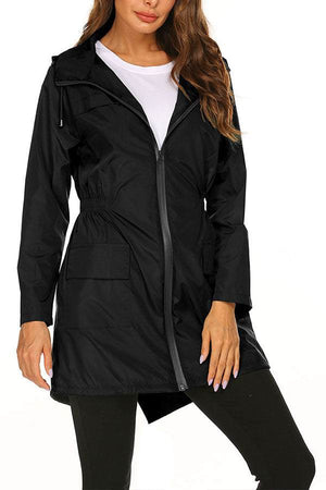 Outdoor and Travel Hooded Raincoat in black lightweight waterproof fabric with front zipper and pockets, worn by woman for travel and outdoor activities