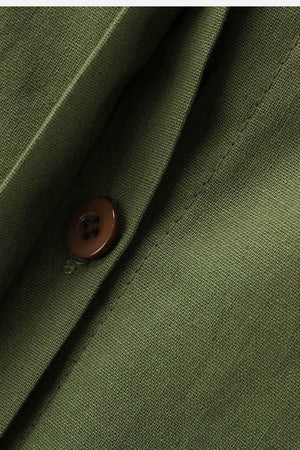Close-up of olive green relaxed shirt and trousers fabric with brown button detail