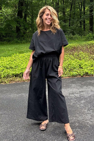 Woman wearing black loose fit co-ord set with wide short sleeves and wide-leg trousers outdoors