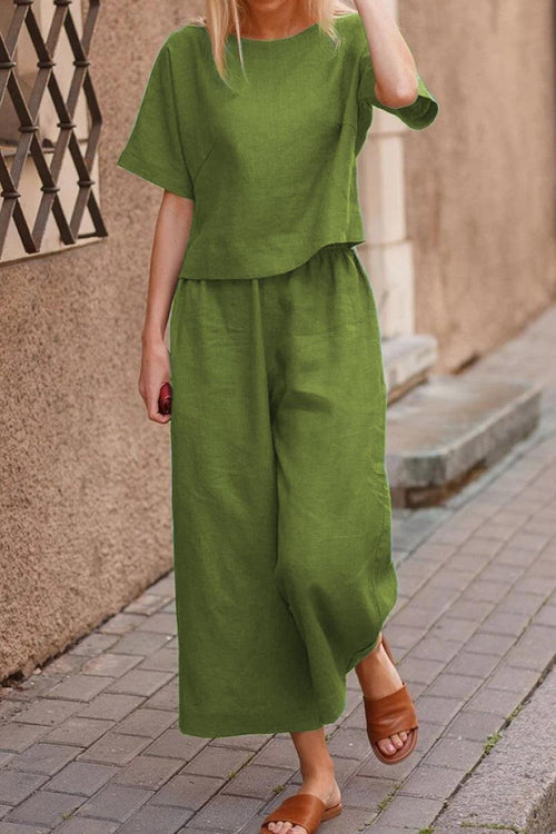 Woman wearing green loose fit co-ord set with wide-leg pants and short-sleeve top walking on sidewalk