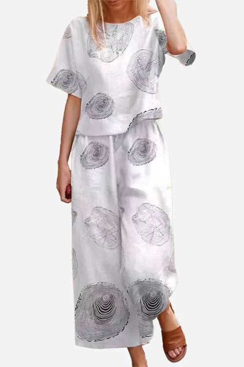 Woman wearing white floral loose fit co-ord set with wide-leg trousers and relaxed short-sleeve top