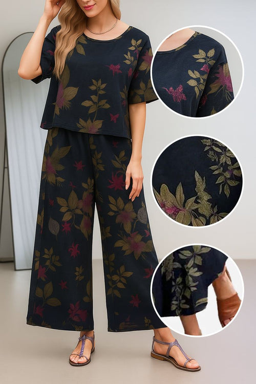 Women wearing a black floral loose fit co-ord set with wide short sleeves and wide-leg trousers, styled with sandals
