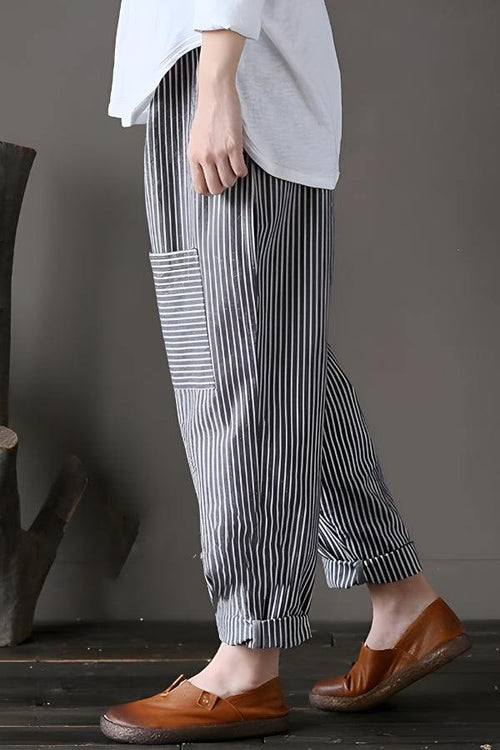 Woman wearing high waist striped black and white comfort pants with side pocket and rolled cuffs.
