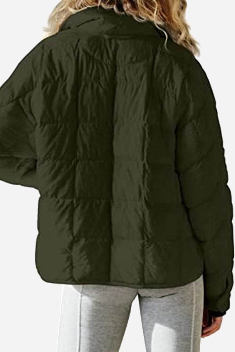 Back view of a woman wearing a dark green lightweight puffer travel jacket with quilted design and long sleeves.