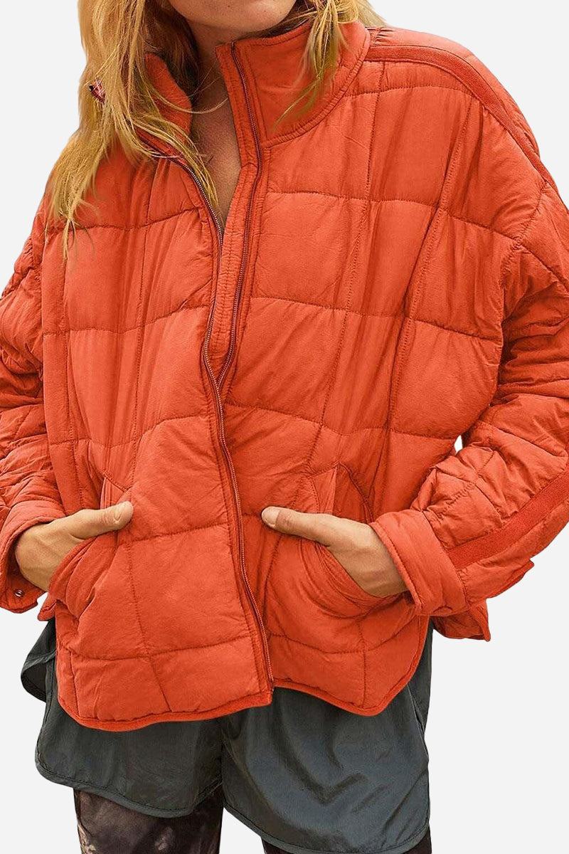 Orange lightweight puffer travel jacket with front pockets and half-zip closure worn by a model