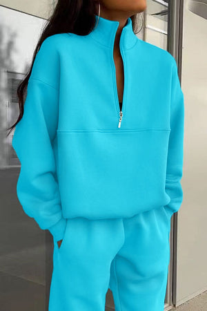 Woman wearing a bright blue cotton-blended two-piece tracksuit with high collar and deep zipper.