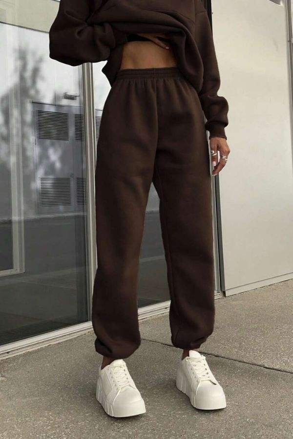 Woman wearing brown cotton-blended two-piece tracksuit pants with white sneakers standing outdoors