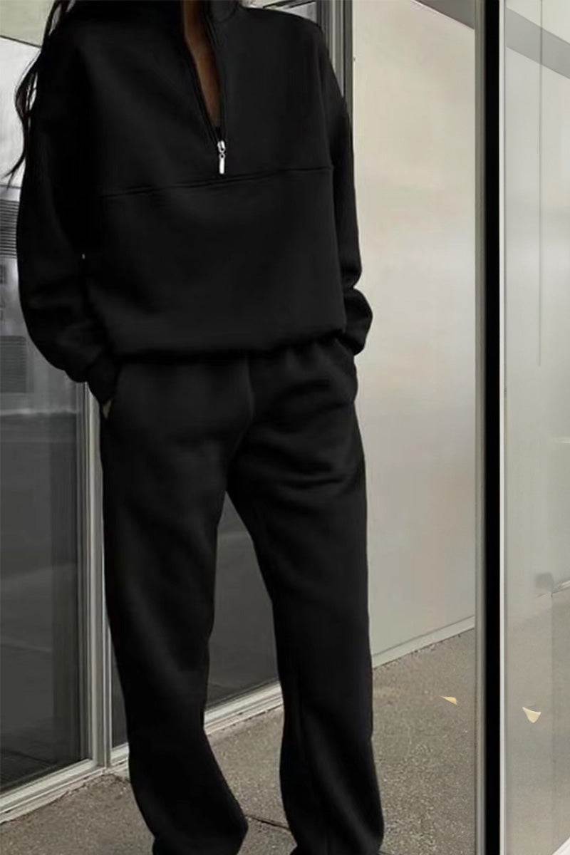 Black cotton-blended two-piece tracksuit with high collar and zipper detail worn indoors