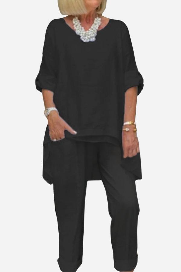 Woman wearing black asymmetrical two-piece trouser set with rolled sleeves and tapered pants