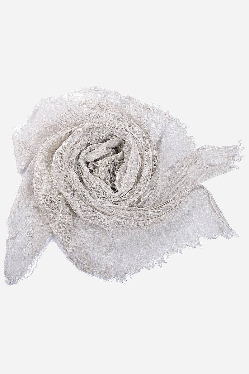White lightweight linen scarf with frayed edges rolled up on a white background