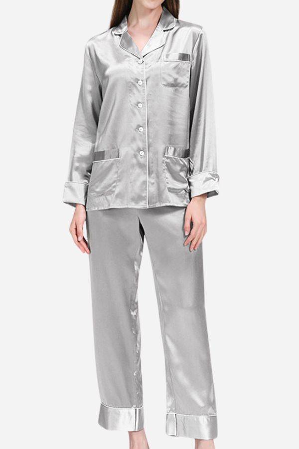 Woman wearing silver long sleeve silk pajamas set with button-up top and matching pants