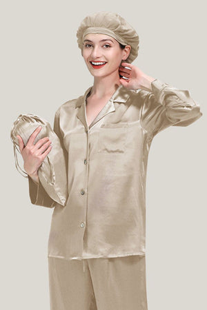 Woman wearing beige Mulberry Silk Pajama Set with matching sleep cap holding a silk pouch against neutral background