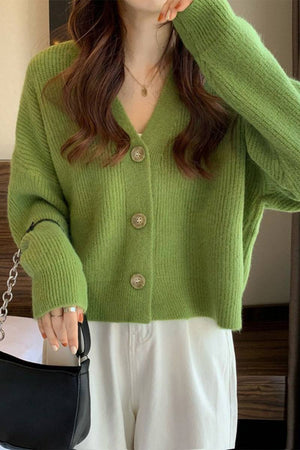 Green casual loose boxy cardigan with buttons worn with white pants and black handbag