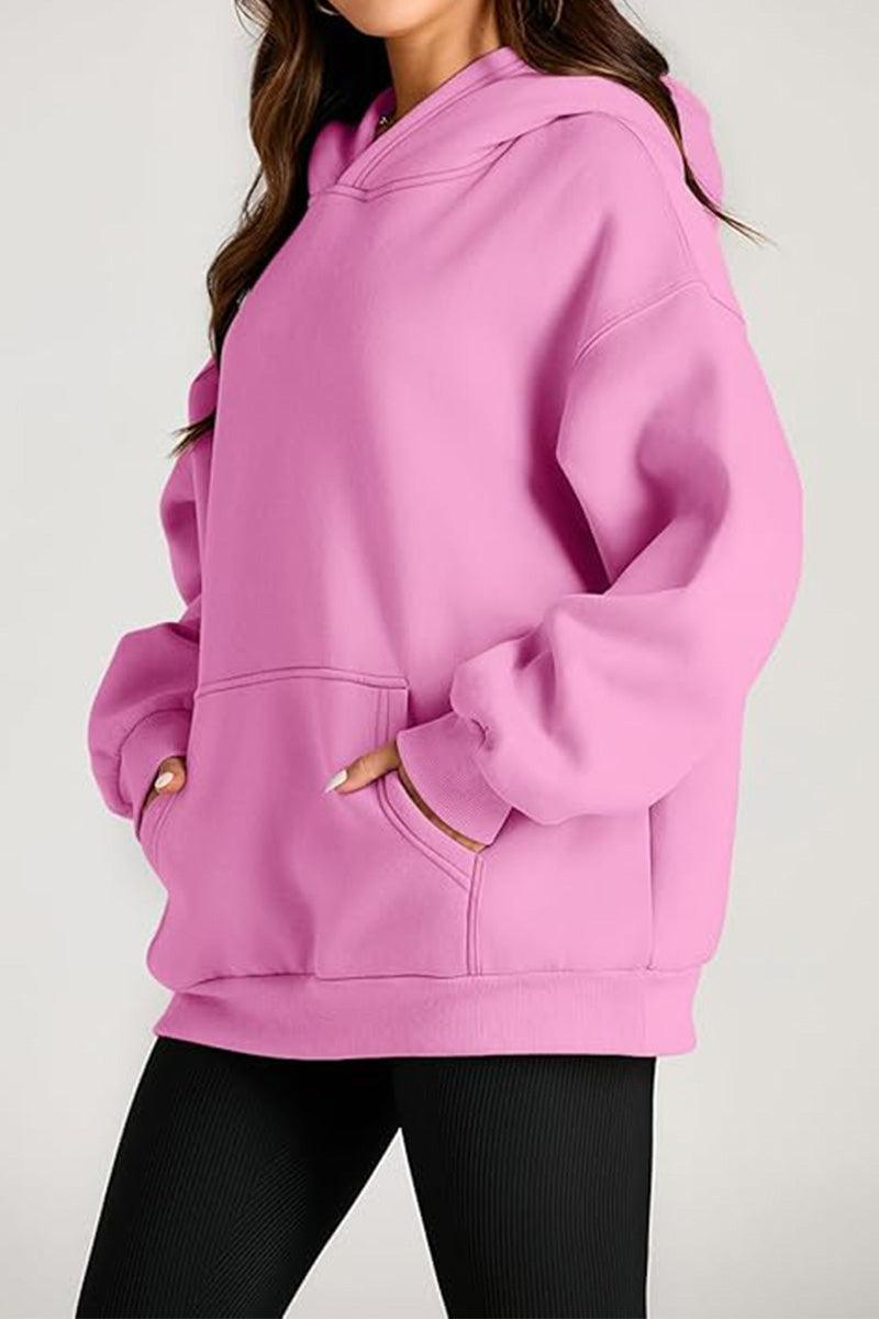 Woman wearing a pink oversized fleece-lined hoodie with front pocket and relaxed fit