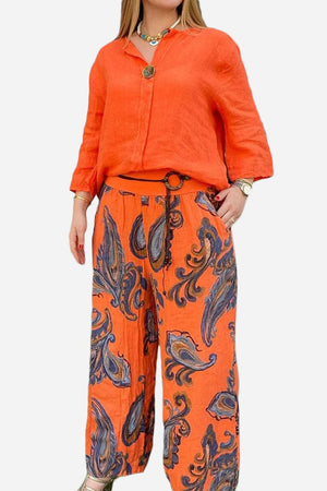Woman wearing orange Vibrant Fusion Two-Piece Set with printed pants and solid top