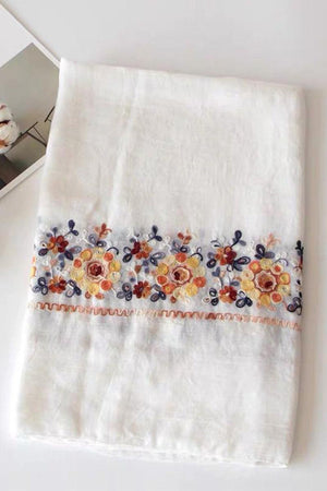 White embroidered travel-must shawl with colorful floral detail, lightweight and versatile wrap for sun protection and style