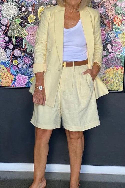 Woman wearing a stylish blazer and shorts two-piece set in light yellow with white top and brown belt.