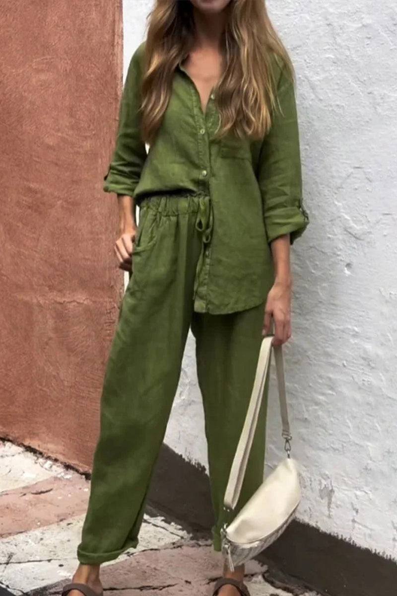 Woman wearing olive green casual chic two-piece set with long sleeves and drawstring pants holding white shoulder bag against textured wall background