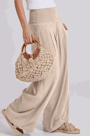 Woman wearing oversized linen blend palazzo pants and holding a woven handbag, part of the Oversized Linen Leaved-IN Set.