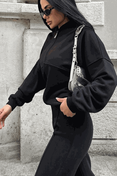 Woman wearing The Voyager Zip Set black zip-front sweatshirt and wide-leg joggers with pockets, styled for comfortable travel and casual wear