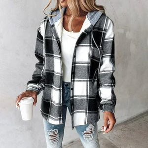 Woman wearing a Highland Plaid Shacket with black, white, and gray plaid, hood, button front, and soft fleece lining, paired with ripped jeans and holding a coffee cup.