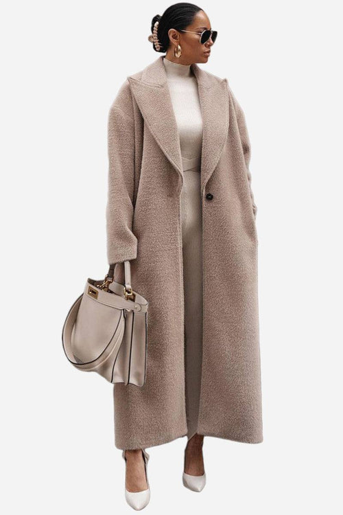 Woman wearing oversized teddy coat in beige with longline silhouette and oversized lapels, styled with matching outfit and handbag