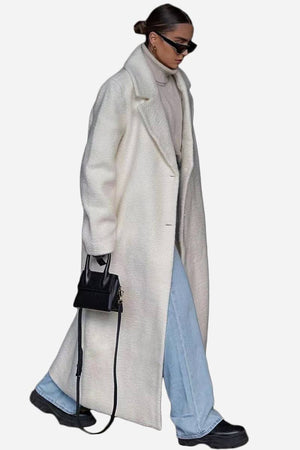 Woman wearing an oversized white teddy coat with turtleneck, light blue jeans, sunglasses, and black handbag.