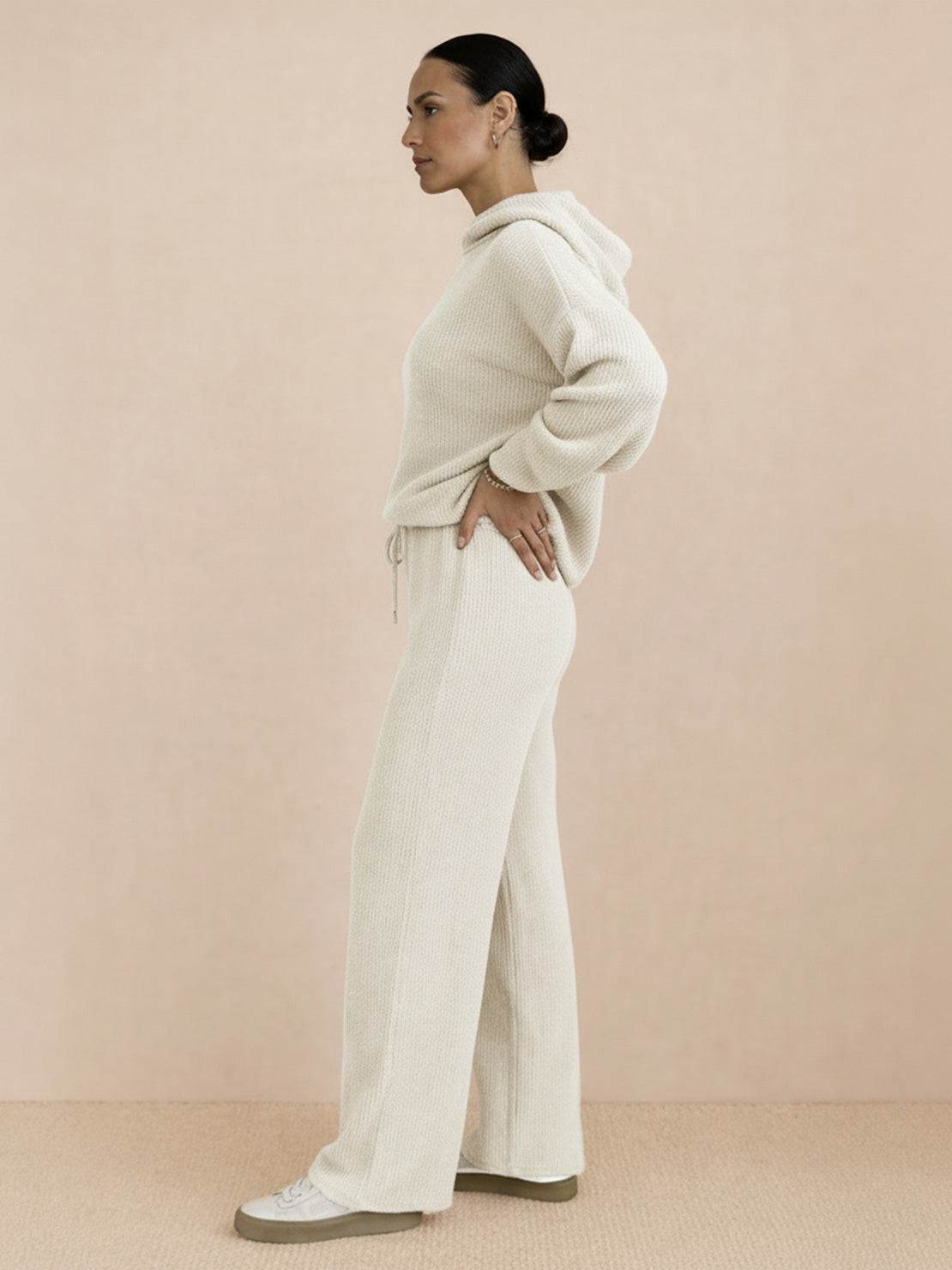 Woman wearing beige waffle-knit two-piece hoodie and pants set, side view, casual comfortable outfit