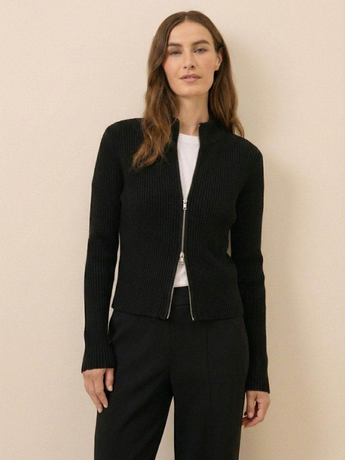 Woman wearing a ribbed zip-up knit cardigan jacket with high neckline and long sleeves