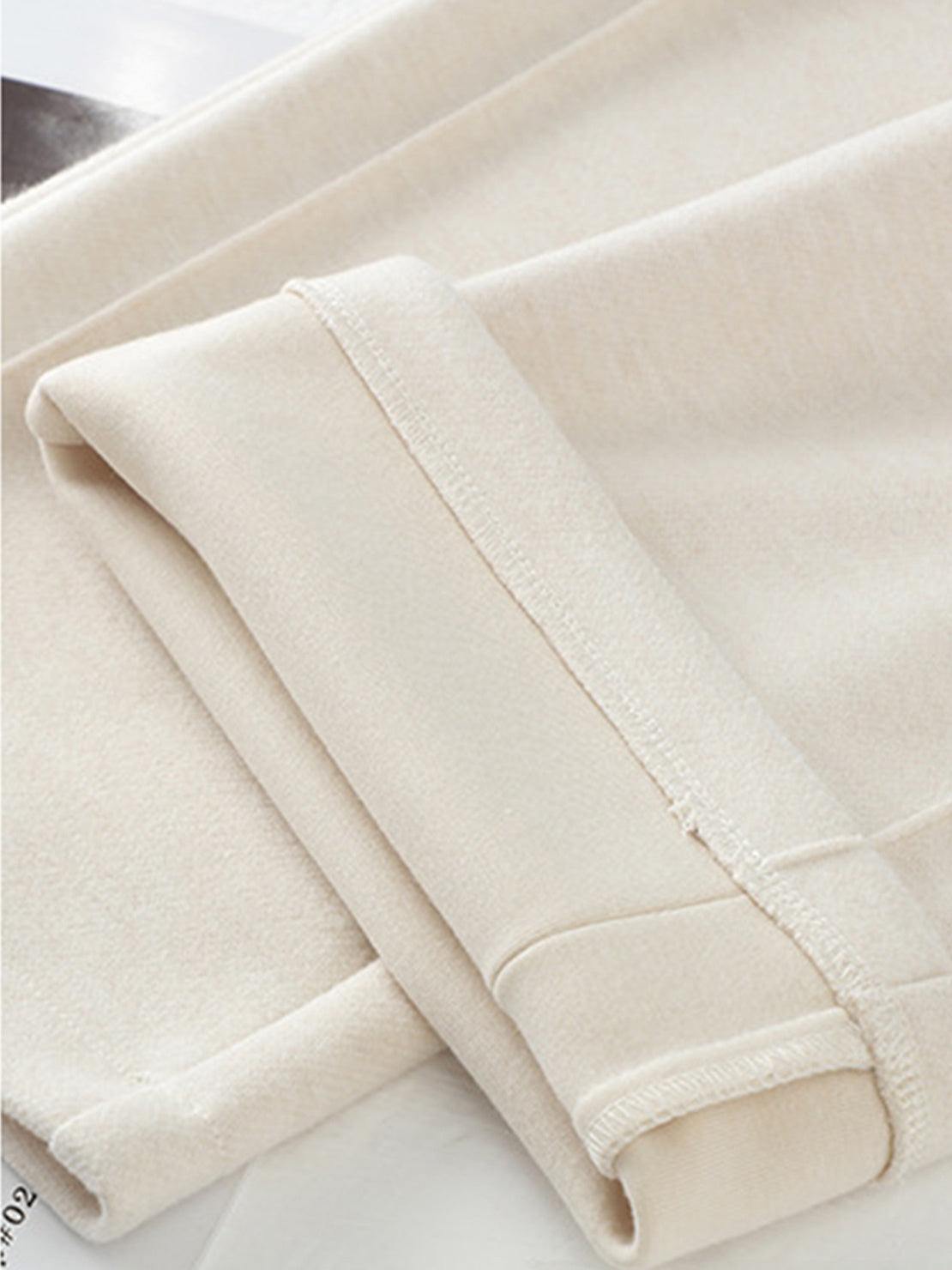 Close-up of beige thermal wool blend trousers fabric with folded hems showing soft texture and stitching details