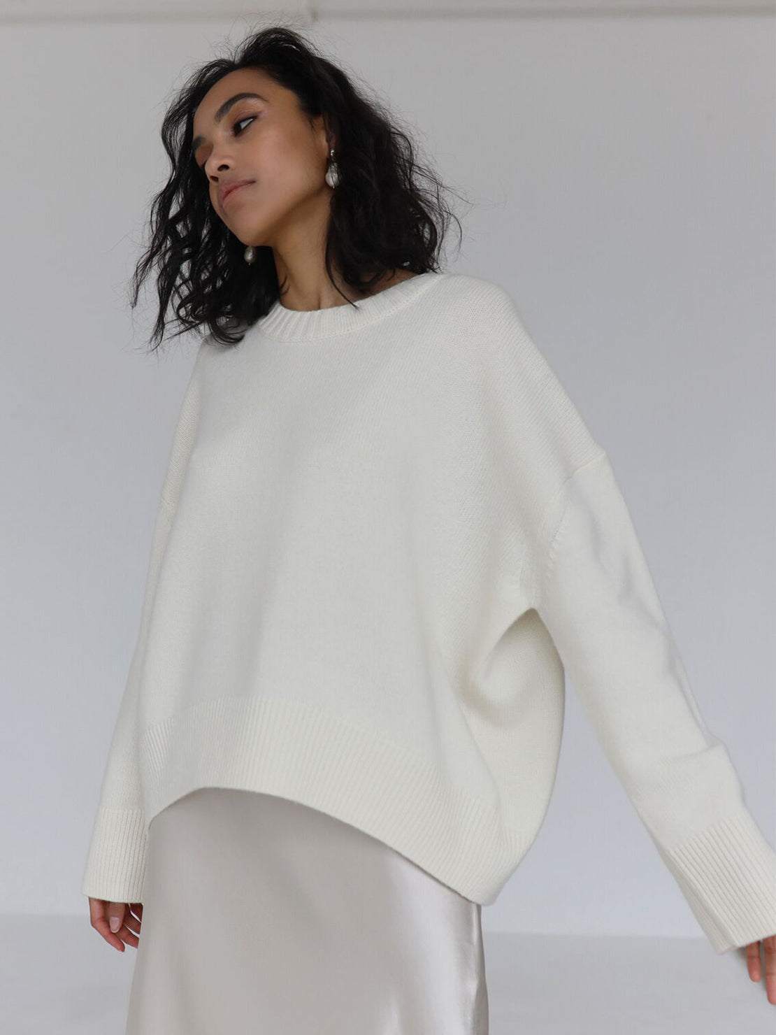 Woman wearing oversized crew neck knit sweater with drop-shoulder sleeves and ribbed cuffs