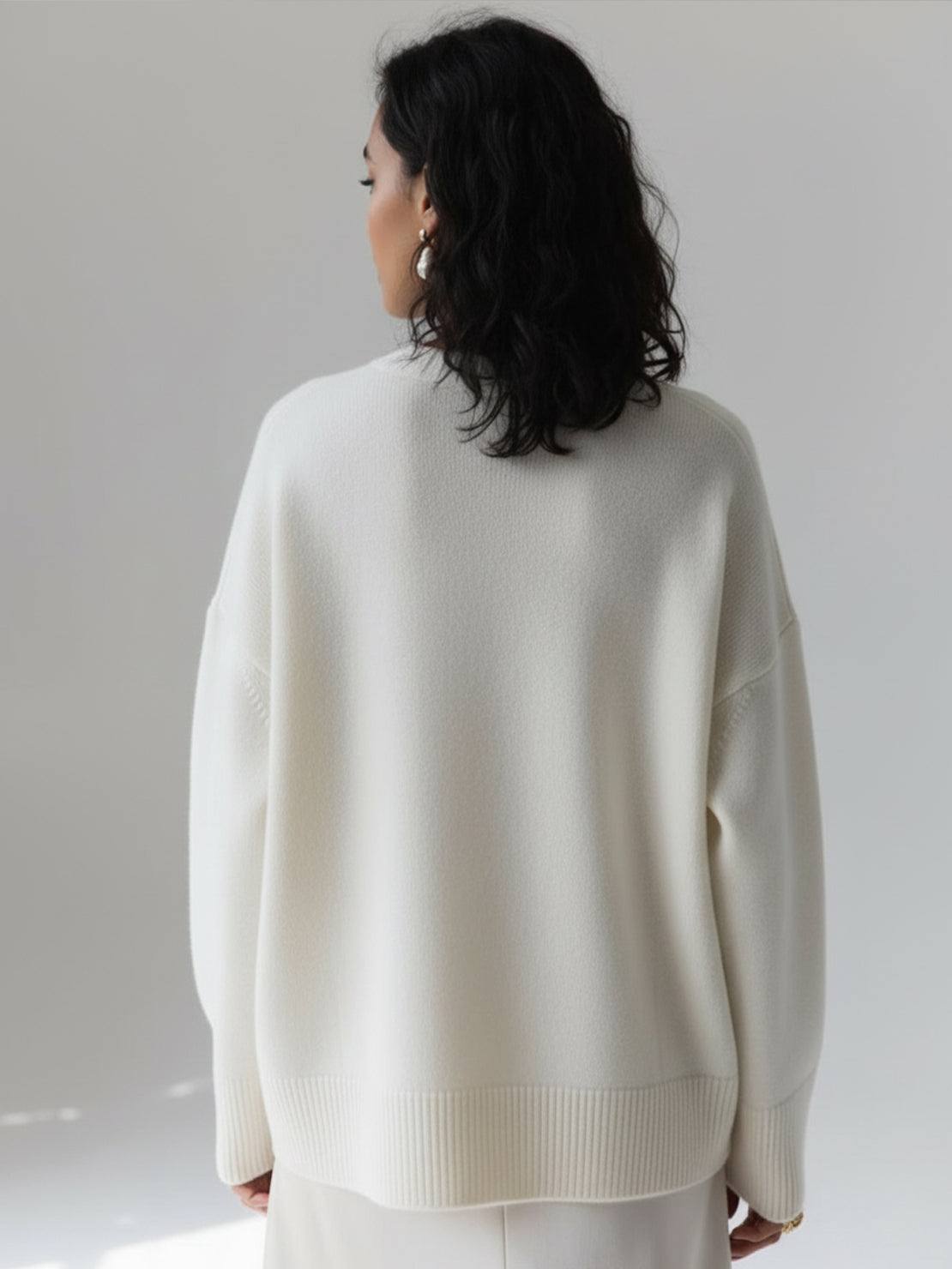 Oversized crew neck knit sweater with drop-shoulder sleeves and ribbed cuffs, in neutral color.