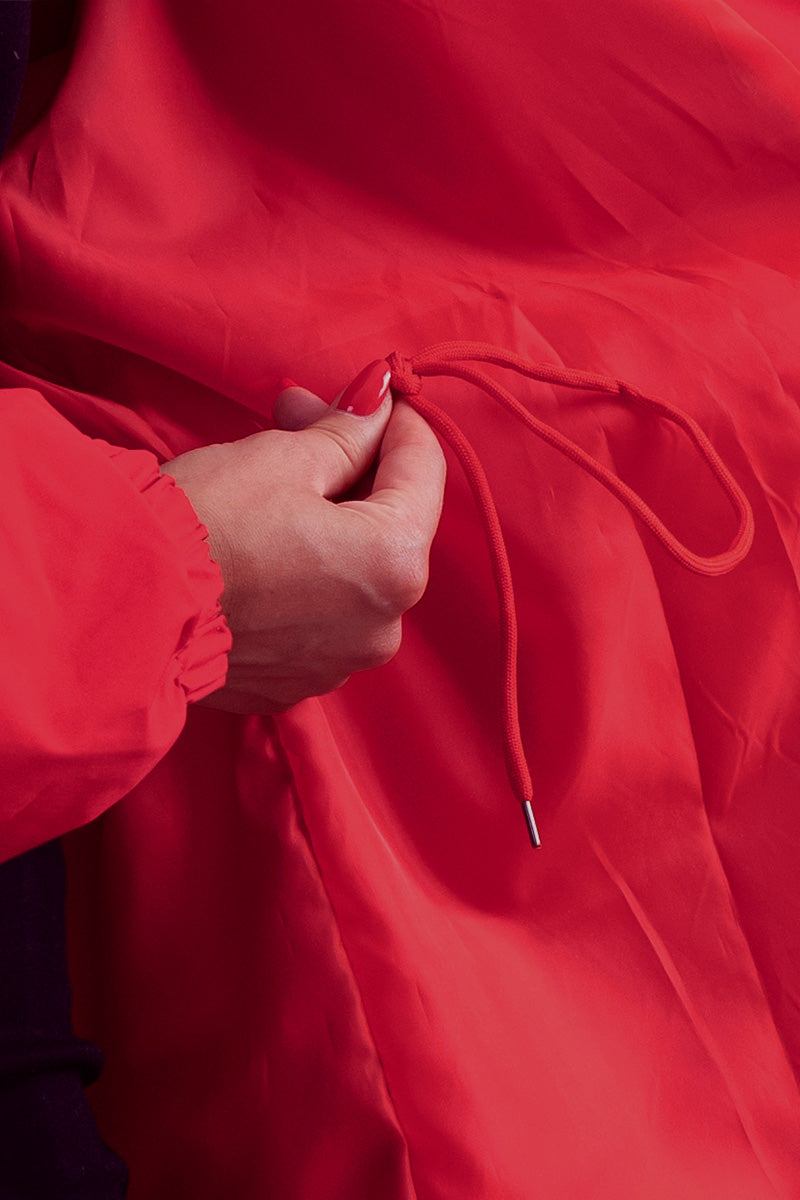 Close-up of red water resistant oversized windbreaker jacket with adjustable drawstring detail