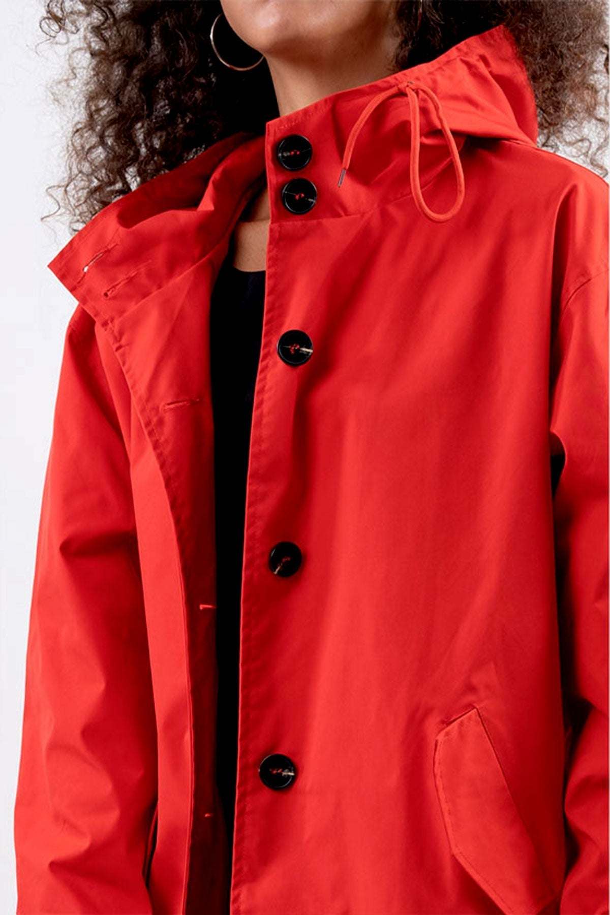 Red oversized water-resistant windbreaker jacket with hood and black buttons.