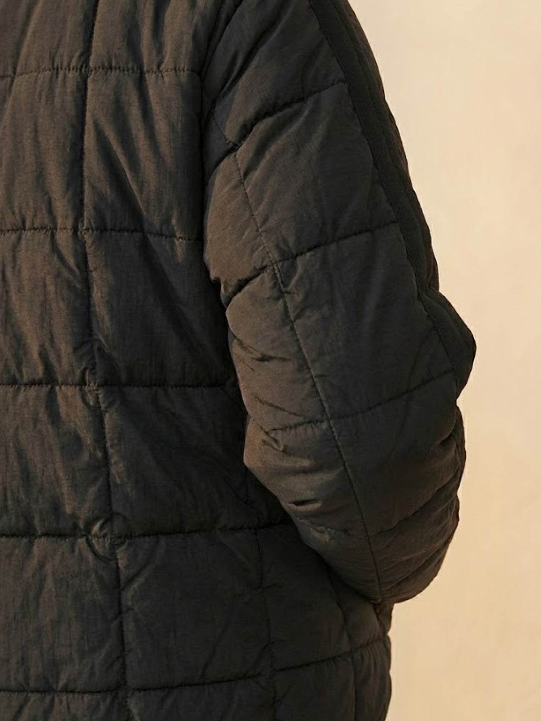 Black lightweight puffer travel jacket with quilted design and soft fabric texture.