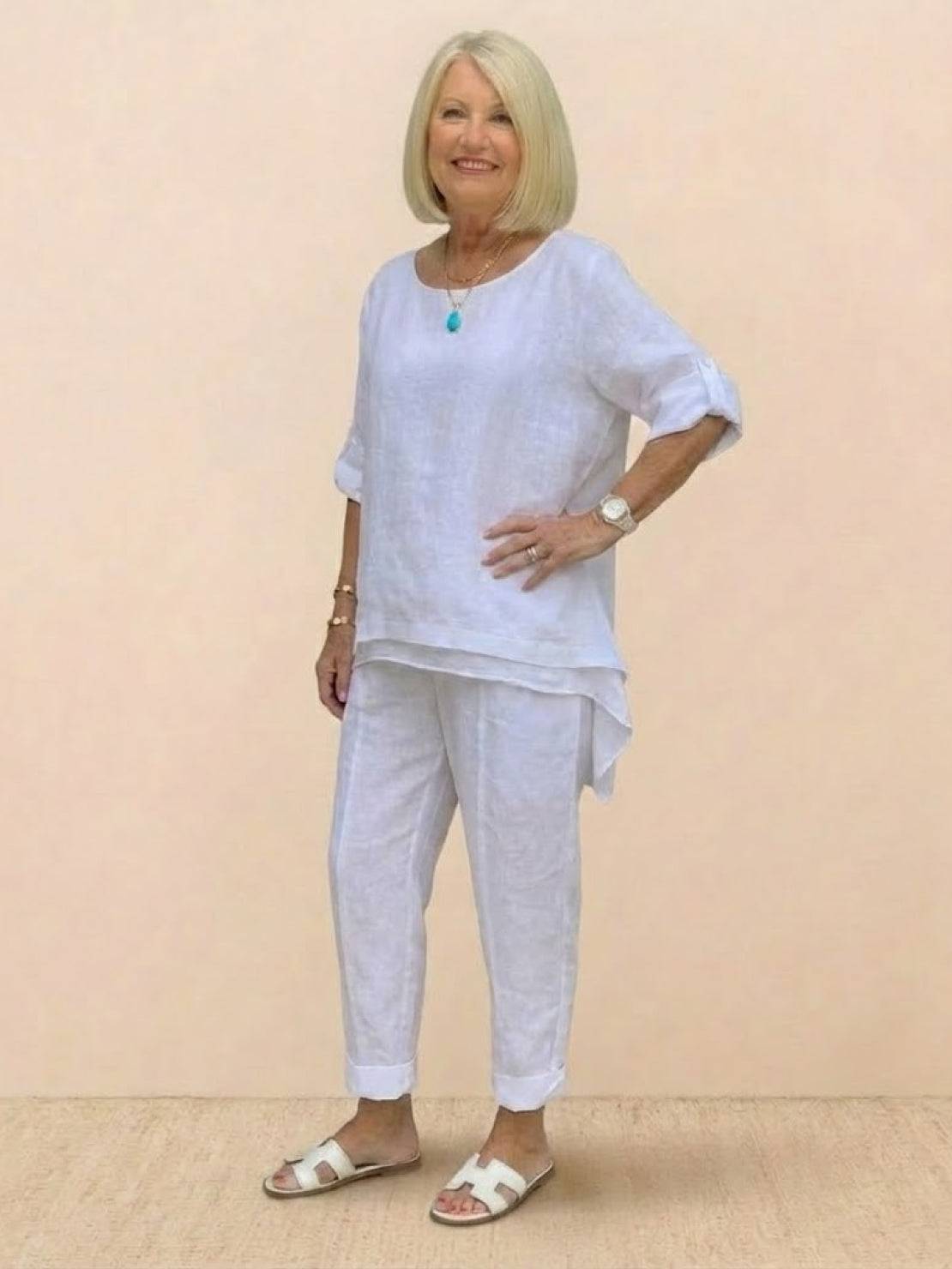 woman wearing white asymmetrical two-piece trouser set with rolled sleeves and tapered pants