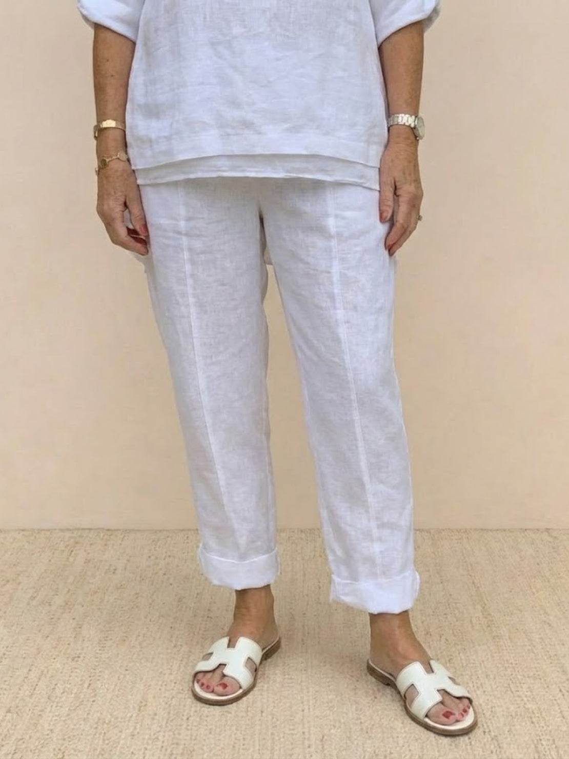 White asymmetrical two-piece trouser set with rolled-up sleeves and slightly tapered pants in breathable linen-like fabric.