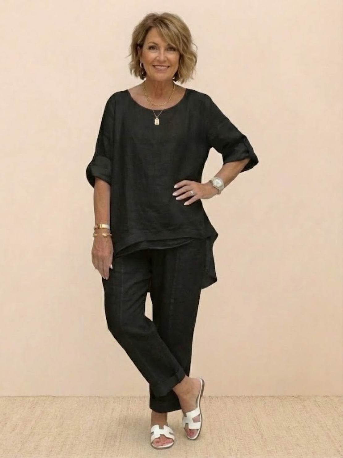 Woman wearing black asymmetrical two-piece trouser set with rolled sleeves and tapered pants