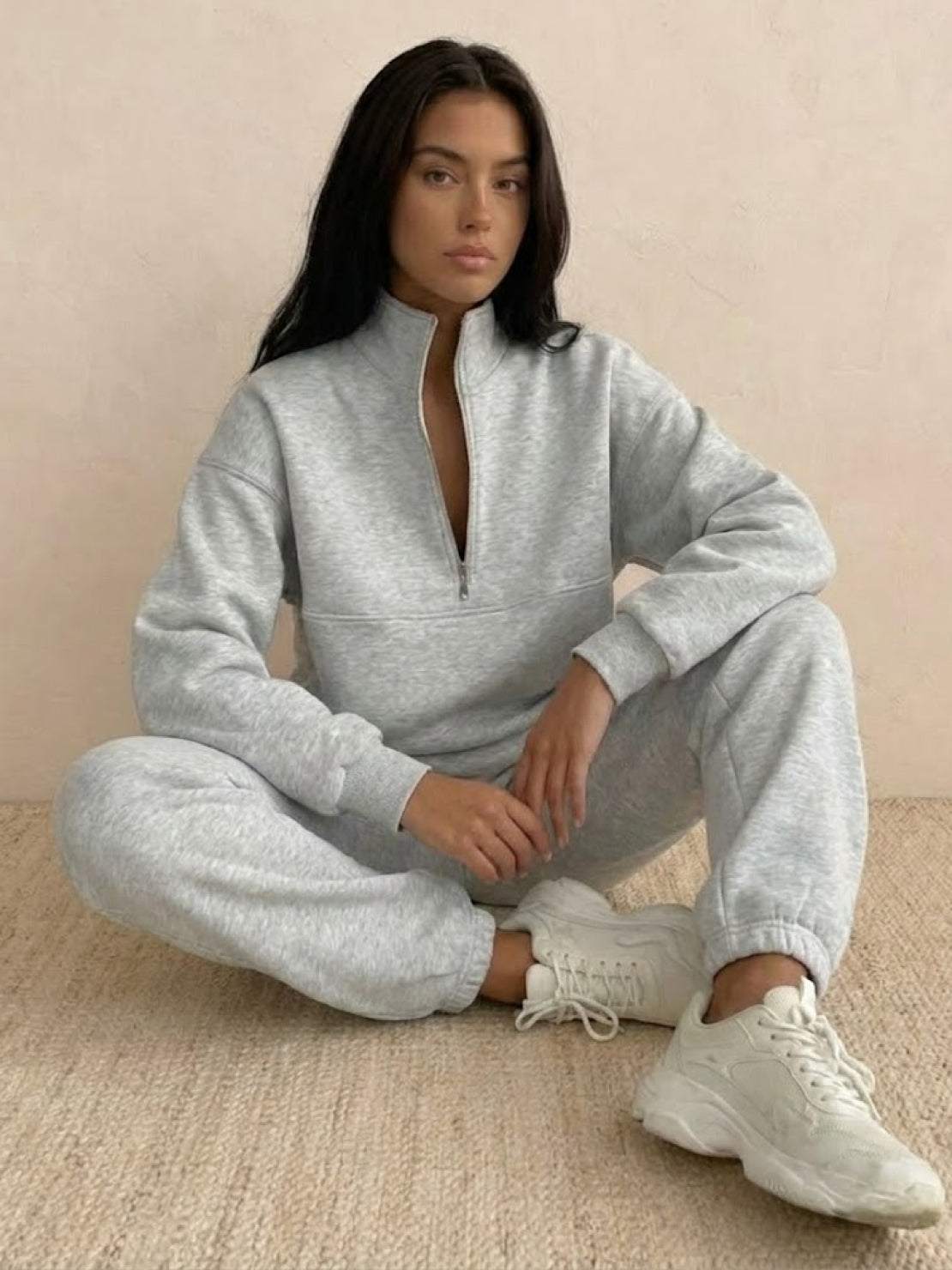 Woman wearing a cotton-blended two-piece tracksuit with high collar and deep zipper, styled for casual confidence and comfort.