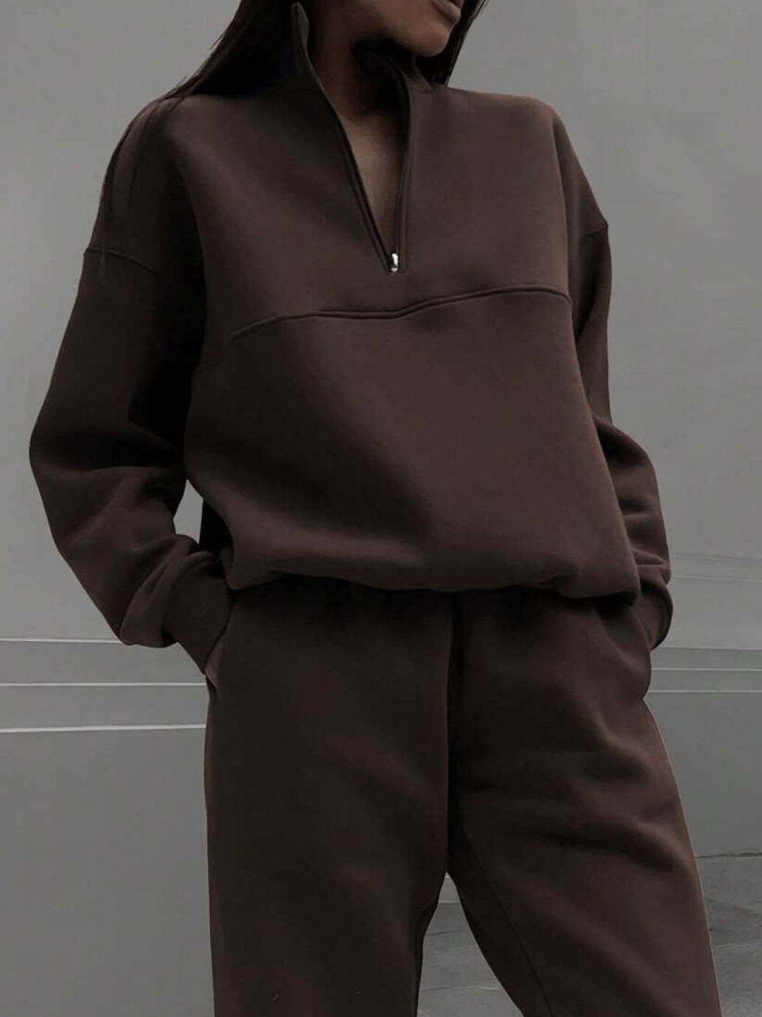 Woman wearing a cotton-blended two-piece tracksuit with high collar and deep zipper for athleisure comfort and style