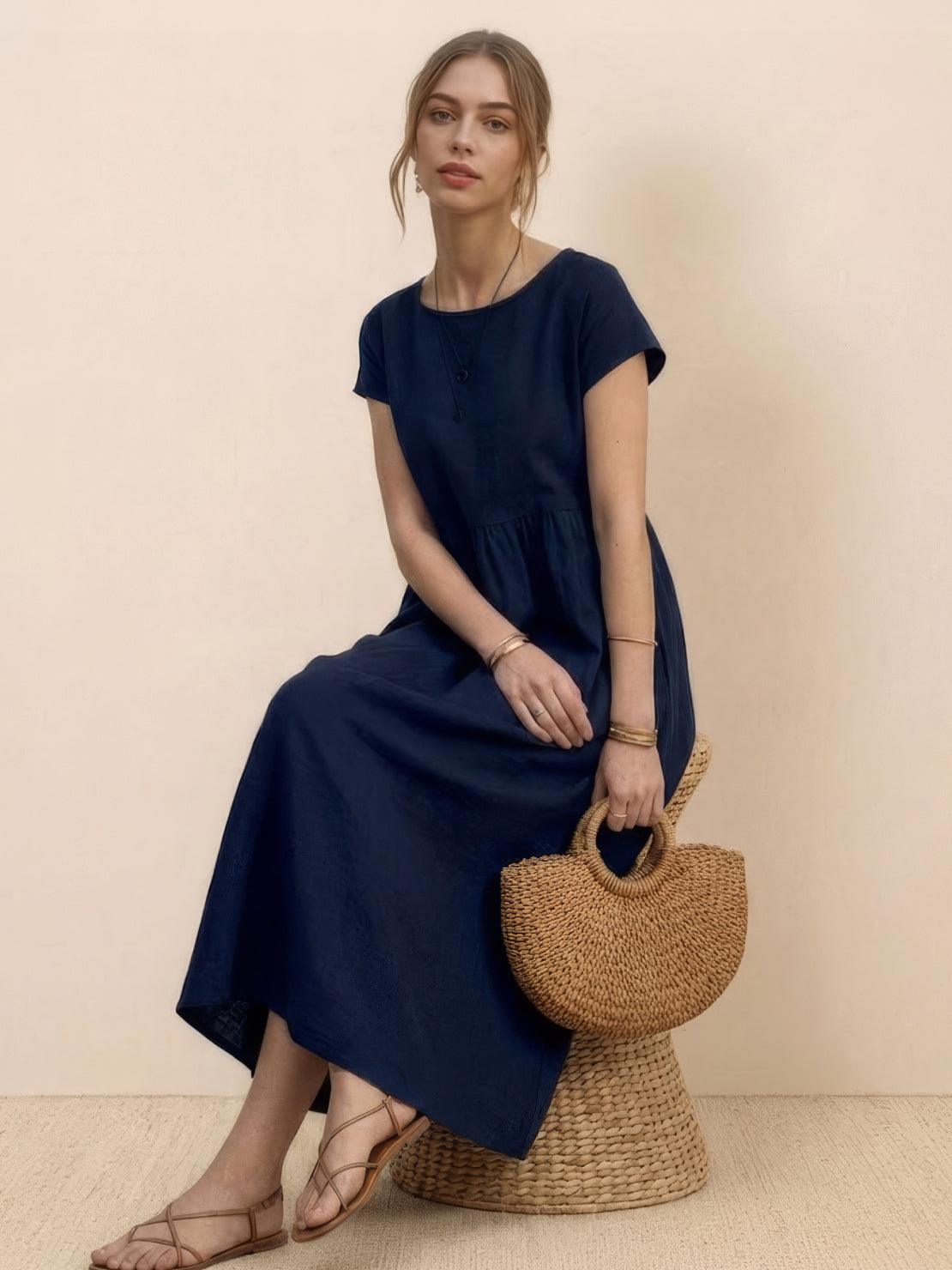 Woman wearing capped-sleeve voluminous pleated midi dress with pockets and flowing skirt