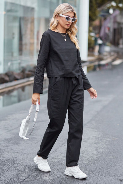 Woman wearing black cotton-linen monochrome capsule set with longline top and wide-leg pants walking on street